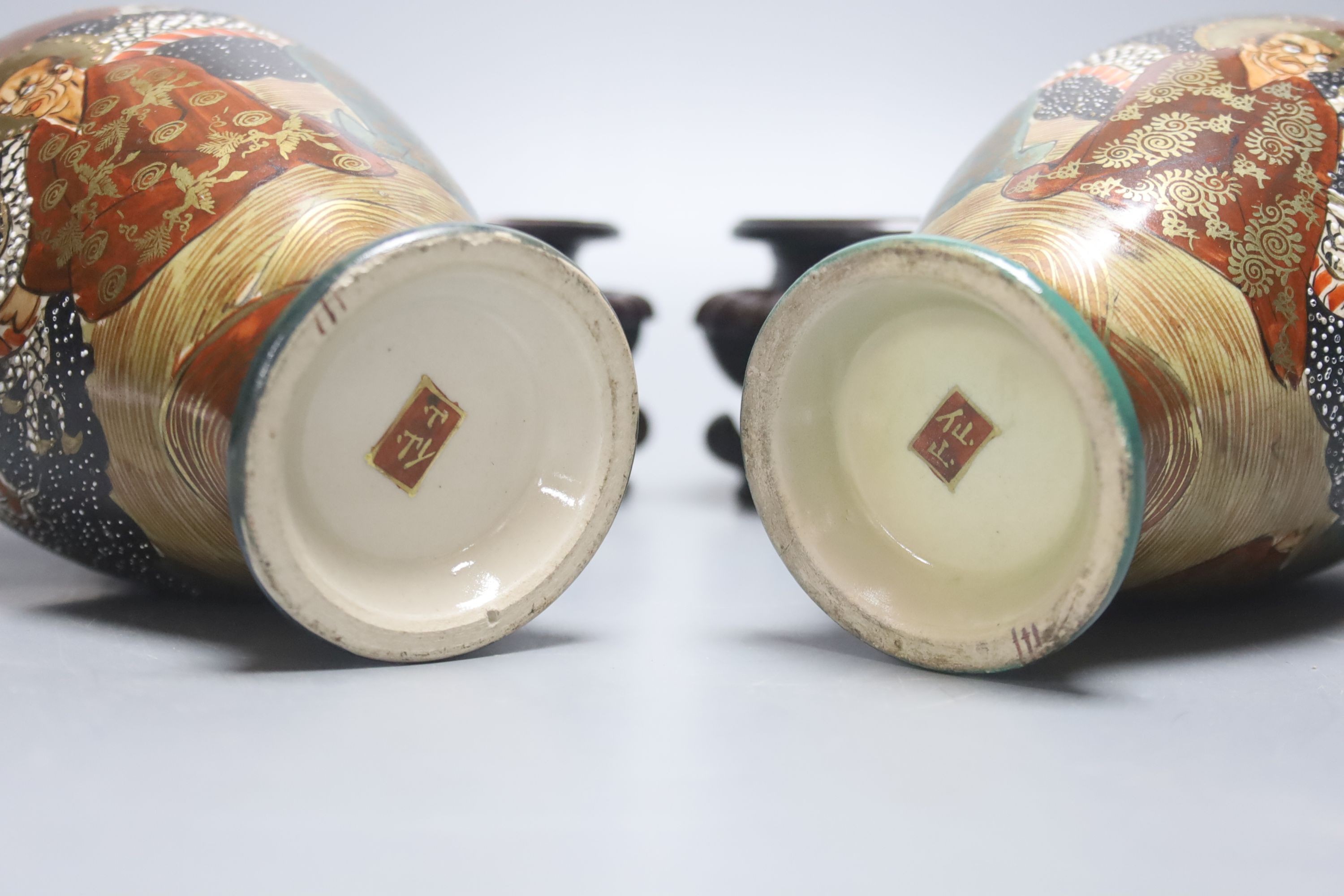 A pair of Japanese Satsuma pottery vases, depicting immortals, 17.5cm, wood stands